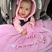Jade is registered to the contest to win money with this photo: baby, blanket, car_interior, car_seat, child, clothing, cozy, cute, expression, face, hood, infant, person, pink_hoodie, portrait, seatbelt, smile, soft_texture, warm, wrapped