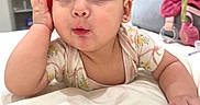 Jade is registered to the contest to win money with this photo: baby, bed, bedding, child, clothing, curious, cute, ears, expression, face, hand, indoor, infant, phone, pink, portrait, room, soft, toy, white