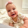 Jade is registered to the contest to win money with this photo: baby, child, smiling, headband, pink_bow, crawling, bed, bedding, blanket, indoor, window_blinds, cute, happy, infant, portrait, person, young_child, soft_light, closeup, cheerful