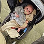 baby, infant, car_seat, pacifier, blanket, stuffed_animal, plush_toy, carpet, floor, footwear, indoor, child, cute, comfort, seated, looking_up, clothing, head, skin, legs