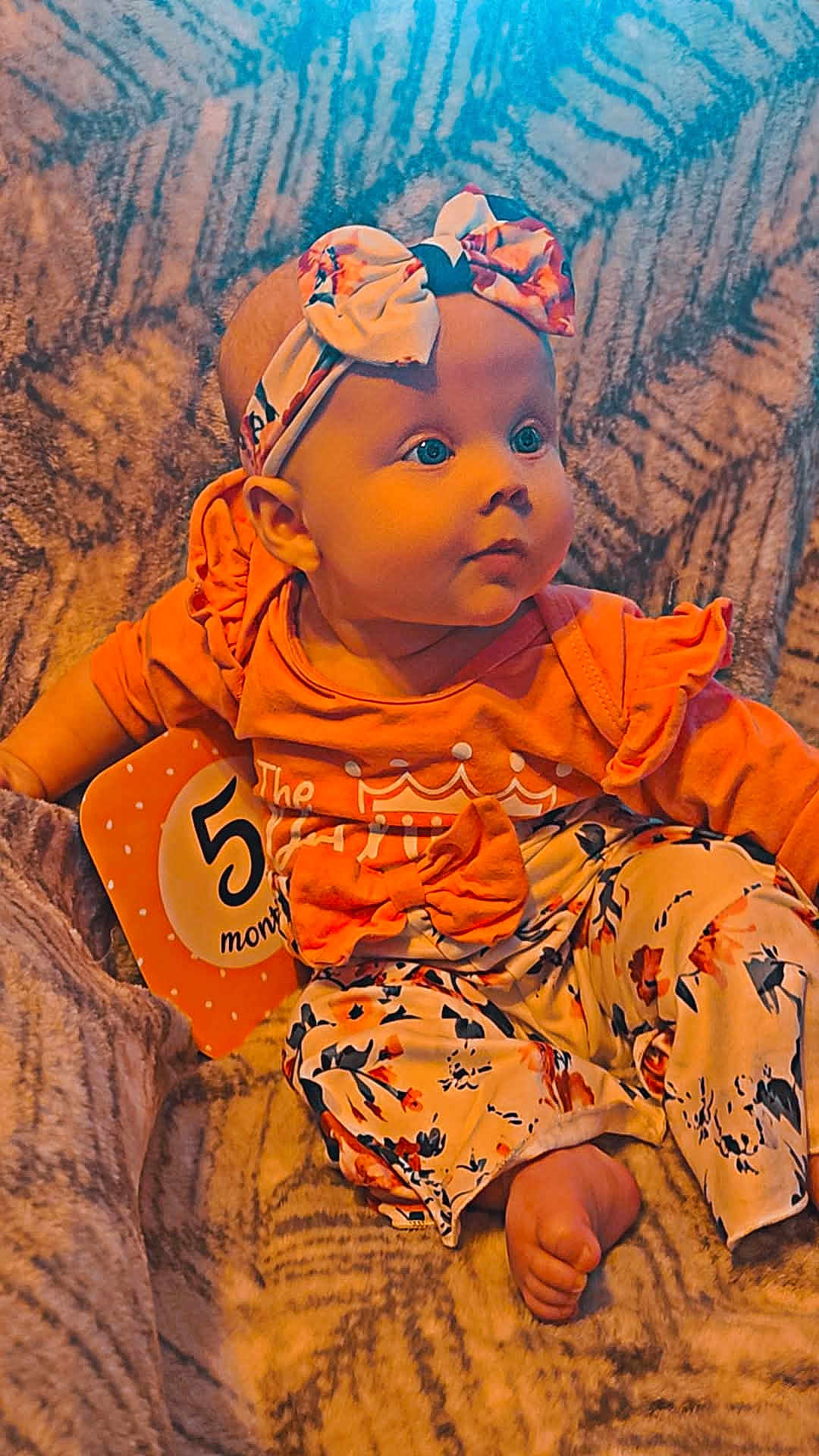 Aurora joined the competition — help win amazing prizes! baby, infant, blue_eyes, headband, bow, orange_clothing, floral_pattern, milestone_card, 5_months, blanket, sitting, cute, child, portrait, indoors, soft_texture, foot, curious, person, smiling