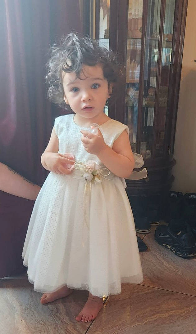 Lea participe au concours pour gagner de l'argent avec cette photo : baby_toddler_clothing, bridal_party_dress, curtain, day_dress, dress, facial_expression, finger, flash_photography, flooring, formal_wear, gesture, happy, iris, long_hair, neck, one_piece_garment, person, shoulder, skin, toddler