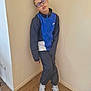 child, person, glasses, sportswear, nike, tracksuit, sneakers, indoor, wooden_floor, beige_wall, standing, casual_pose, young_person, footwear, floor, clothing, portrait, leaning, eyewear, relaxed