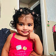Shivanshi joined the competition — help win amazing prizes! bag, carpet, cheeky_expression, child, curly_hair, cute, doorframe, face, hair_clips, hand, holding, indoor, person, pink_clothing, polka_dot, portrait, smiling, toddler, wall_decoration, young_child