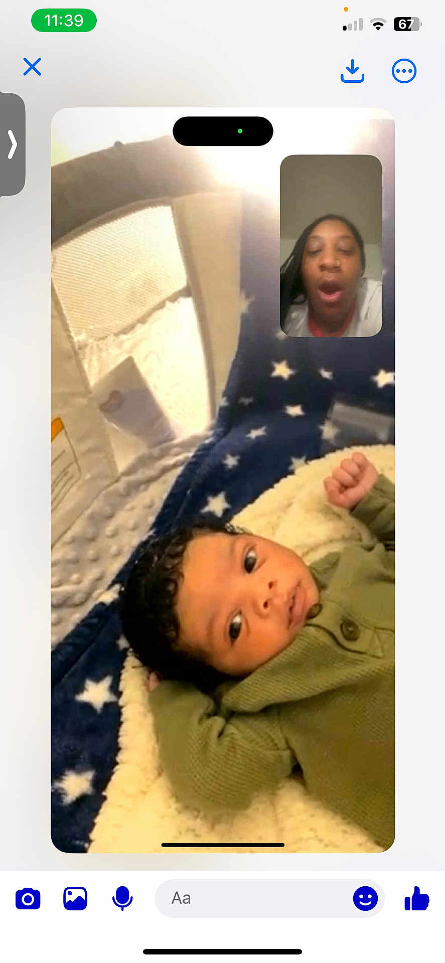 Tavon is registered to the contest to win money with this photo: baby, blanket, clothing, communication, curly_hair, expression, face, green_sweater, home, indoor, infant, lying_down, person, portrait, screen, soft_texture, stars, technology, video_call, yawning