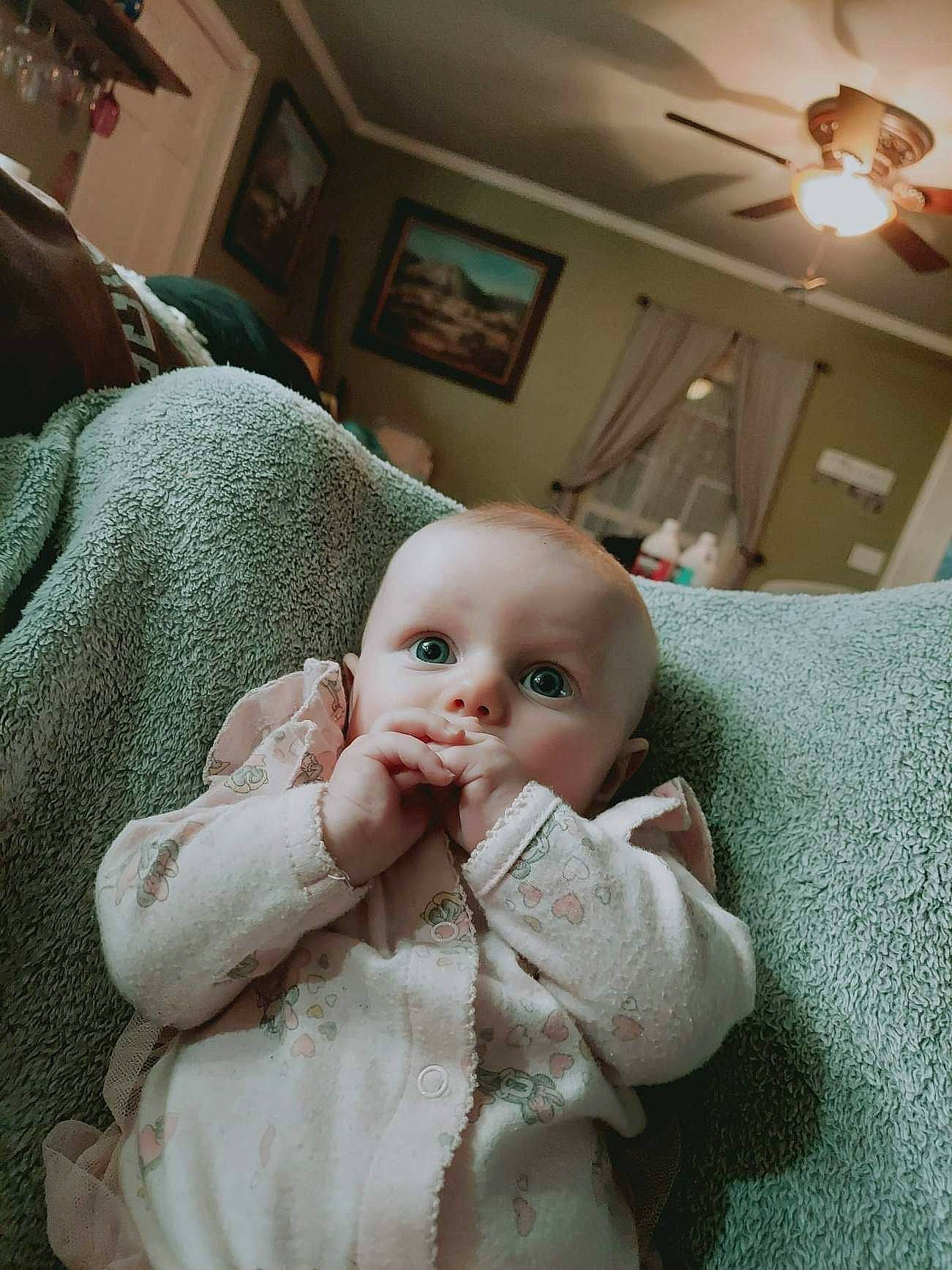 Emmaline joined the competition — help win amazing prizes! baby, baby_toddler_clothing, ceiling, chair, cheek, child, comfort, fur, gesture, hat, lamp, light_fixture, person, picture_frame, room, sconce, sitting, skin, sun_hat, thumb