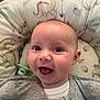 Francesca is registered to the contest to win money with this photo: baby, infant, smiling, happy, face, eyes, mouth, clothing, gray_shirt, cushion, dinosaur_print, pattern, soft, indoor, child, cute, joyful, portrait, head, skin