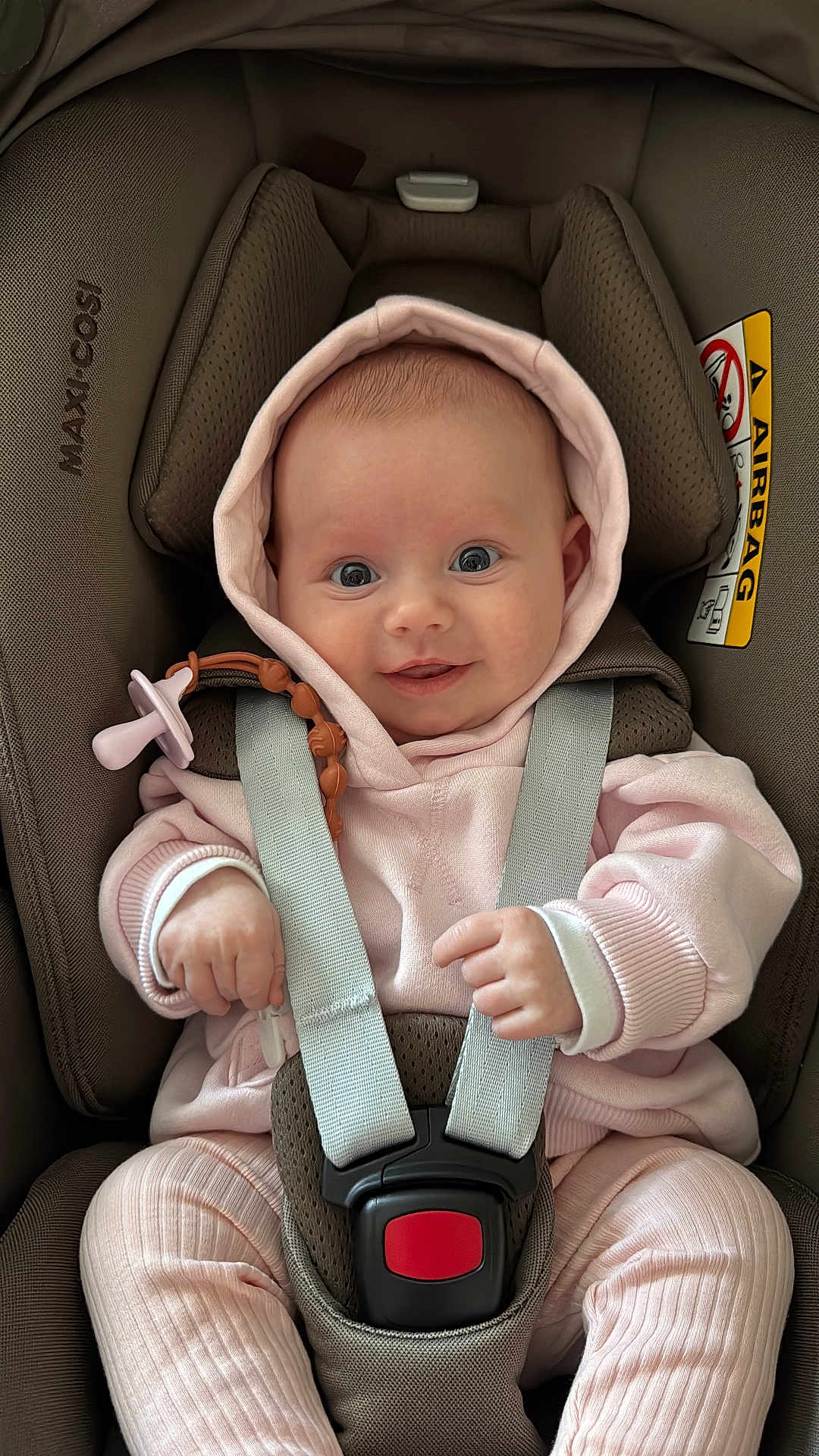 Francesca is registered to the contest to win money with this photo: baby, infant, car_seat, maxi_cosi, pink_clothing, hoodie, pacifier, baby_strap, smiling, wide_eyes, cute, cozy, child, seatbelt, safety, indoor, portrait, happy, hands, soft_texture