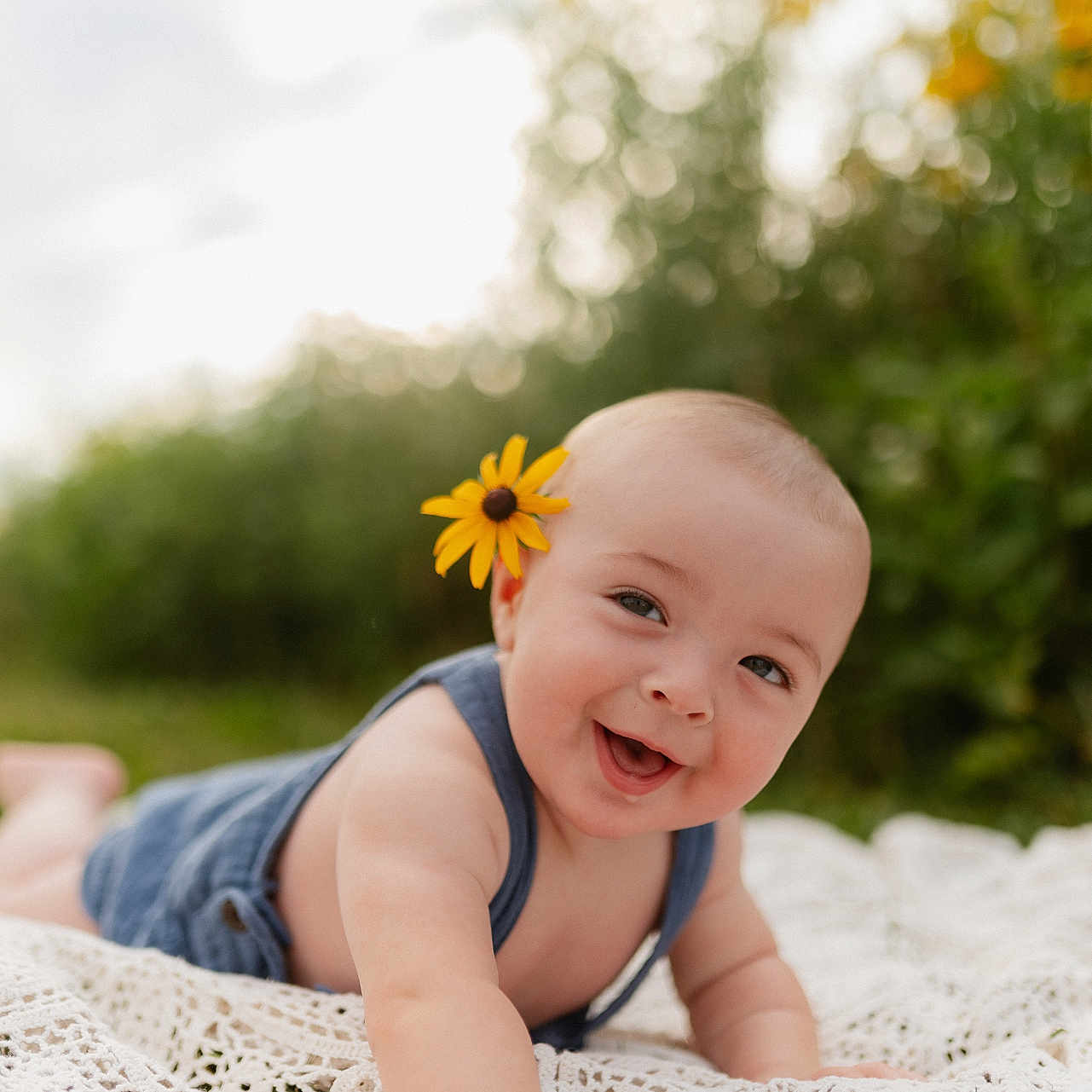 Graysen joined the competition — help win amazing prizes! baby, smiling, flower, outdoor, blanket, greenery, happy, infant, portrait, nature, sunlight, cute, toddler, head, skin, clothing, grass, young_child, relaxing, daylight
