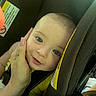 baby, child, car_seat, hand, manicure, smile, face, infant, seatbelt, safety, yellow_clothing, close_up, portrait, indoors, cute, person, skin, head, eyes, baby_carrier