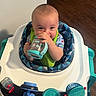 Graysen joined the competition — help win amazing prizes! baby, infant, child, sippy_cup, bib, baby_walker, toy, indoor, floor, wooden_floor, happy, smiling, face, person, clothing, seat, blue, green, feeding, cute