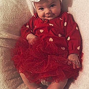 Layla joined the competition — help win amazing prizes! baby, infant, child, red_dress, tutu_skirt, headband, bow, socks, blanket, smile, cute, portrait, indoors, soft_texture, happy, sitting, face, person, clothing, cozy