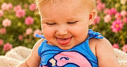 Ember joined the competition — help win amazing prizes! baby, blanket, blonde_hair, blue_outfit, child, cute, flamingo_design, flowers, greenery, happy, nature, outdoor, pigtails, pink_flowers, pink_hair_clips, portrait, sitting, smiling, sunlight, tongue_out