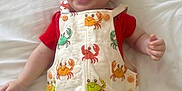 Edison is registered to the contest to win money with this photo: baby, infant, smiling, happy, cute, clothing, romper, crab_pattern, red_shirt, bed, white_bedspread, lying_down, cheerful, child, person, skin, face, hand, blue_eyes, short_hair