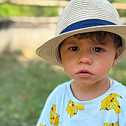 Imanol participe au concours pour gagner de l'argent avec cette photo : boy, casual, child, clothing, curious, daylight, expression, face, fashion, fence, greenery, hat, nature, outdoor, pikachu, portrait, shirt, summer, toddler, young