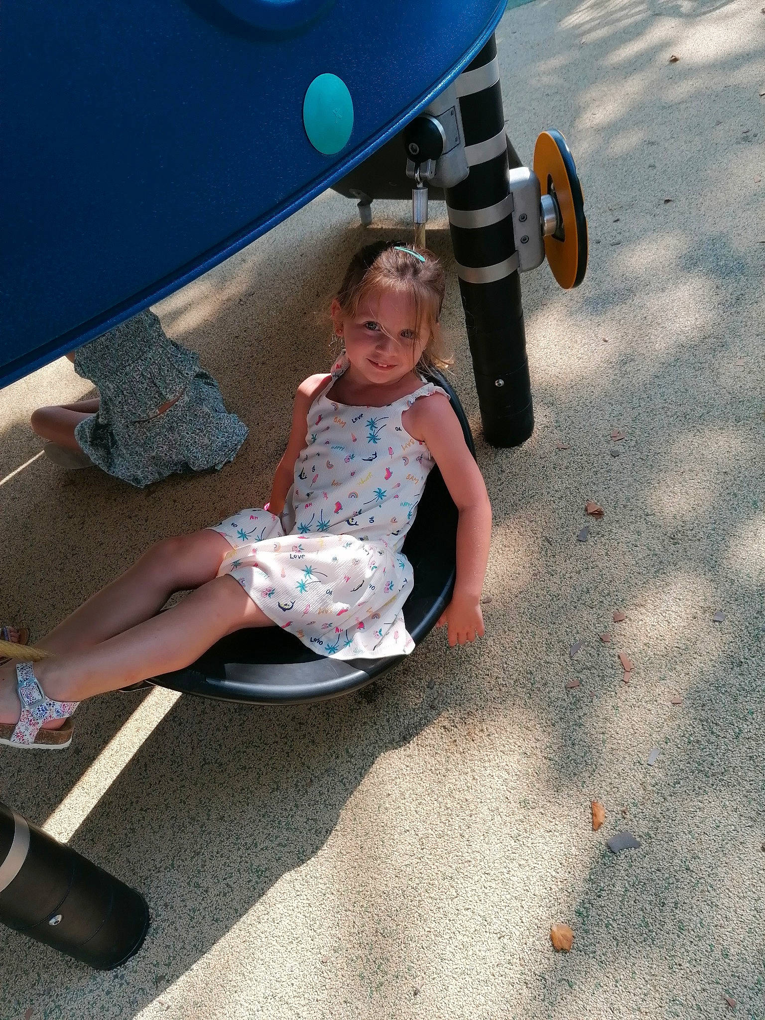 Emma a rejoint le concours — aidez-le/la à gagner de superbes lots ! asphalt, automotive_tire, bumper, child, city, electric_blue, fun, human_leg, joy, knee, leisure, outdoor_play_equipment, person, play, recreation, road_surface, sandal, shadow, sitting, sock