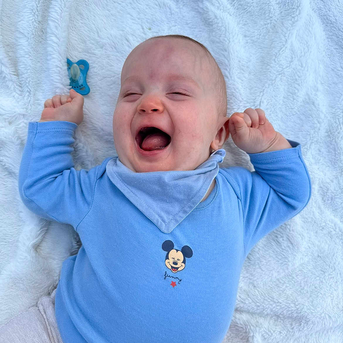 Jules participe au concours pour gagner de l'argent avec cette photo : baby, infant, smiling, laughing, blue_onesie, mickey_mouse, pacifier, blanket, happy, child, cute, lying_down, clothing, face, person, young_child, infant_toys, soft_texture, joyful, playful