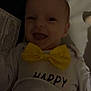 baby, infant, bow_tie, smiling, happy, clothing, face, expression, indoors, portrait, child, cute, joy, apparel, closeup, person, newborn, cheerful, dark, fabric