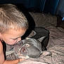 child, dog, bed, blanket, indoor, affection, love, pet, animal, face, closeup, resting, cute, bond, tender, cozy, young, skin, fur, touch