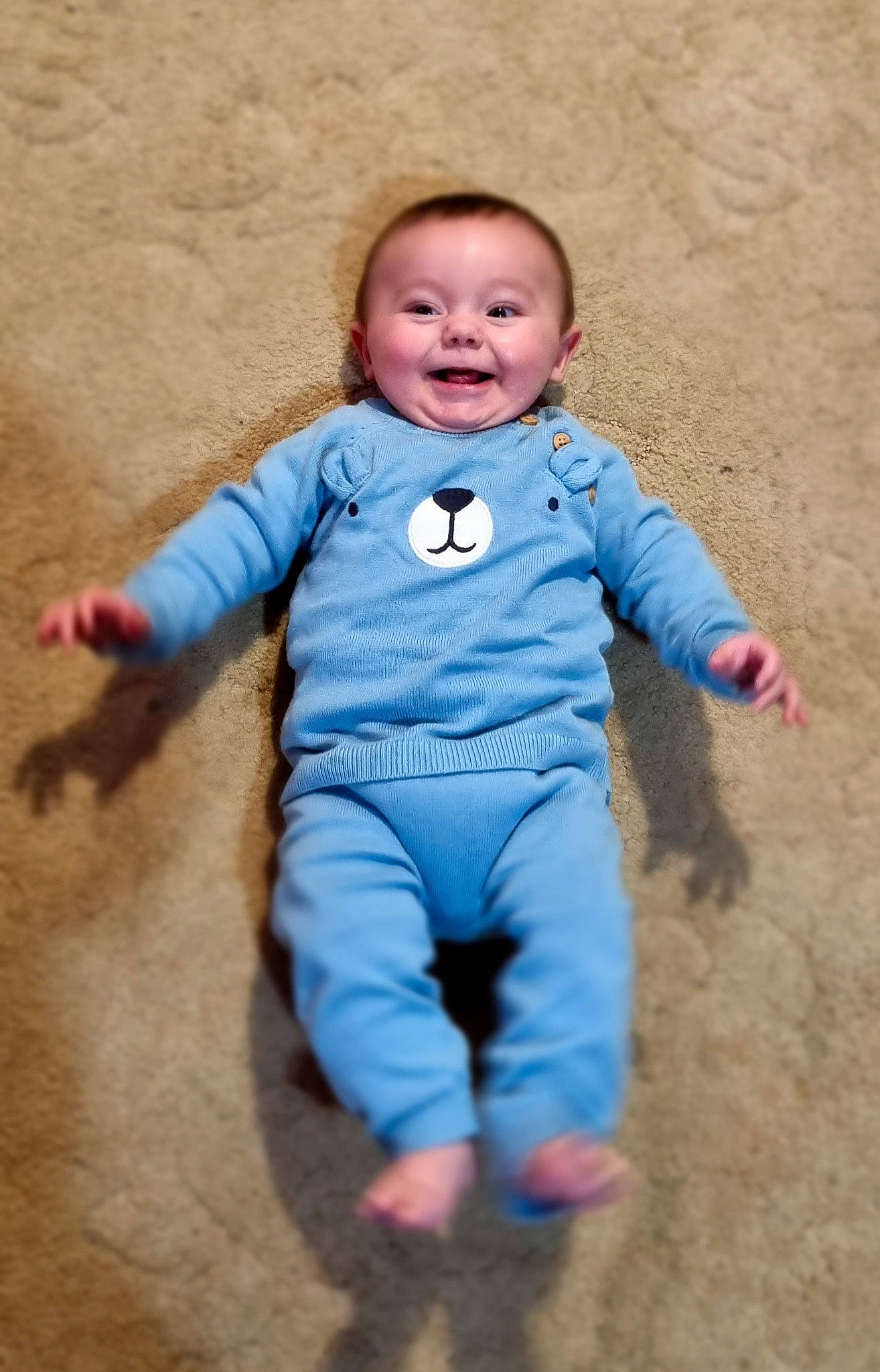 Kenzo is registered to the contest to win money with this photo: arm, baby_toddler_clothing, cheek, clothing, eye, face, finger, flooring, gesture, hand, happy, head, joy, mammal, nose, outerwear, people_in_nature, person, skin, sleeve