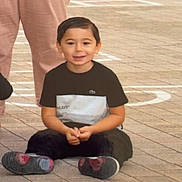 Ayden participe au concours pour gagner de l'argent avec cette photo : child, boy, smiling, sitting, outdoor, pavement, casual_clothing, short_hair, person, adult, pants, sneakers, black_shirt, green_sweater, cross_legged, street, daylight, happy, young, portrait