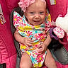 baby, infant, child, smiling, headband, flower, pink, car_seat, colorful_clothing, floral_pattern, happy, cute, portrait, indoors, young_child, seat_belt, toy, soft_toys, fabric, close_up