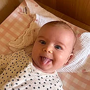 Elsie joined the competition — help win amazing prizes! baby, infant, tongue_out, polka_dot, onesie, blanket, pink, checkered, wooden, crib, cute, smiling, expression, face, head, child, indoors, cozy, soft, playful