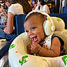 baby, headphones, smiling, infant, dinosaur, inflatable, seat, people, indoor, casual, joyful, child, cute, happy, clothing, table, can, background, woman, fun