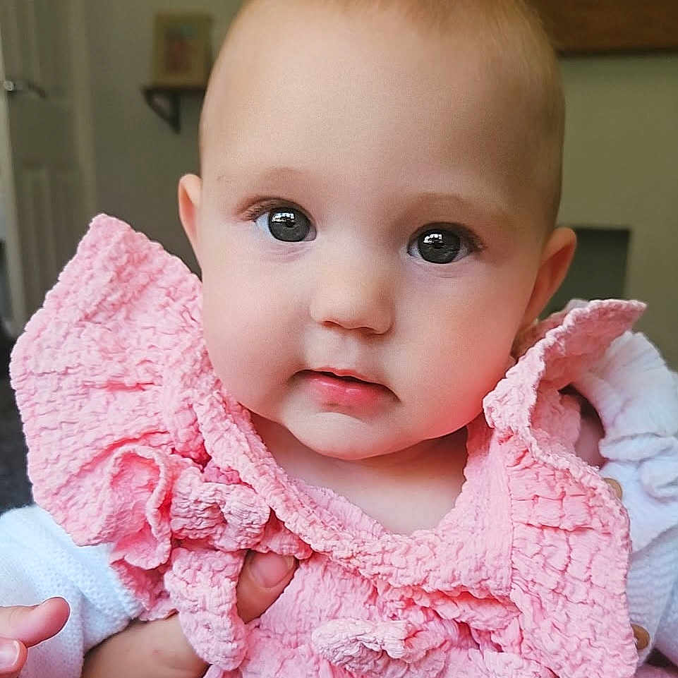 Harper joined the competition — help win amazing prizes! adorable, baby, child, closeup, clothing, curious, cute, expression, eyes, face, head, indoor, infant, person, pink_clothing, portrait, skin, small_hands, soft_texture, young_child