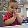 baby, child, high_chair, red_shirt, clapping, smiling, indoor, modern_interior, stone_wall, ceiling_lights, person, happy, cute, toddler, portrait, furniture, playful, young, seat, home