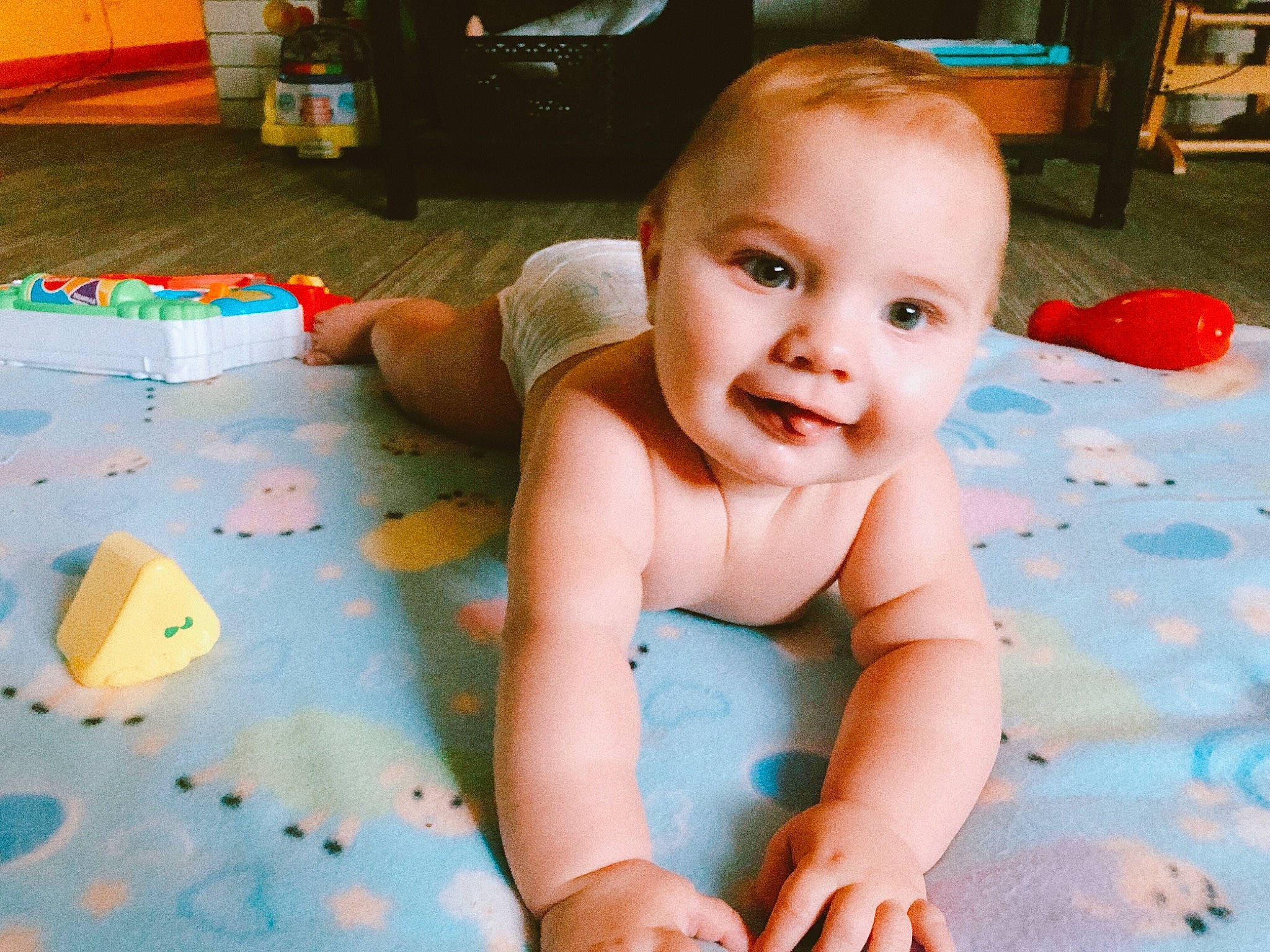 Desmond is registered to the contest to win money with this photo: baby, baby_toddler_clothing, cheek, child, crawling, face, floor, flooring, fun, head, joy, leisure, person, play, skin, smile, toddler, toy, tummy_time, vacation