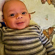 Dawson is registered to the contest to win money with this photo: baby, infant, smile, face, eyes, striped_clothing, blanket, cartoon, soft, lying_down, child, cute, young, portrait, person, indoors, cozy, happy, head, clothing