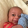 Dawson is registered to the contest to win money with this photo: baby, infant, smiling, cute, red_shirt, blue_mitten, blanket, closeup, face, cheeky, happy, lying_down, soft_texture, cozy, skin, expression, young_child, cute_face, small_hand, indoors