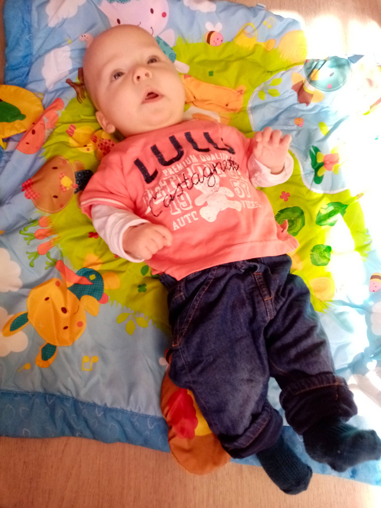 Lylio participe au concours pour gagner de l'argent avec cette photo : baby, baby_products, baby_toddler_clothing, cheek, child, comfort, fun, happy, linens, magenta, orange, pattern, person, pink, play, purple, room, sitting, sleeve, t_shirt