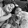 Juan is registered to the contest to win money with this photo: baby, black_and_white, child, clothing, curly_hair, cushion, cute, face, happy, indoor, infant, lying_down, onesie, pattern, person, portrait, resting, sibling, smile, toddler