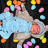 Juan joined the competition — help win amazing prizes! baby, newborn, onesie, hoodie, striped_clothing, blue_clothing, plastic_eggs, easter_eggs, colorful, yellow, pink, orange, light_blue, black_background, blanket, infant, laying_down, cute, face, baby_hat