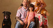 Kalani joined the competition — help win amazing prizes! family, portrait, man, woman, child, girl, dog, rottweiler, small_dog, pet, chair, smiling, happy, casual_clothing, floral_dress, indoor, studio, seated, tattoo, footwear