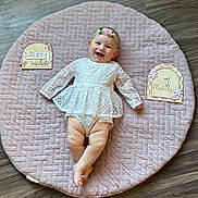 Erin joined the competition — help win amazing prizes! baby, infant, smiling, happy, girl, lace_dress, headband, flower, quilted_mat, pink, wooden_floor, milestone, age_sign, name_sign, crawling_mat, cute, portrait, child, indoor, celebration