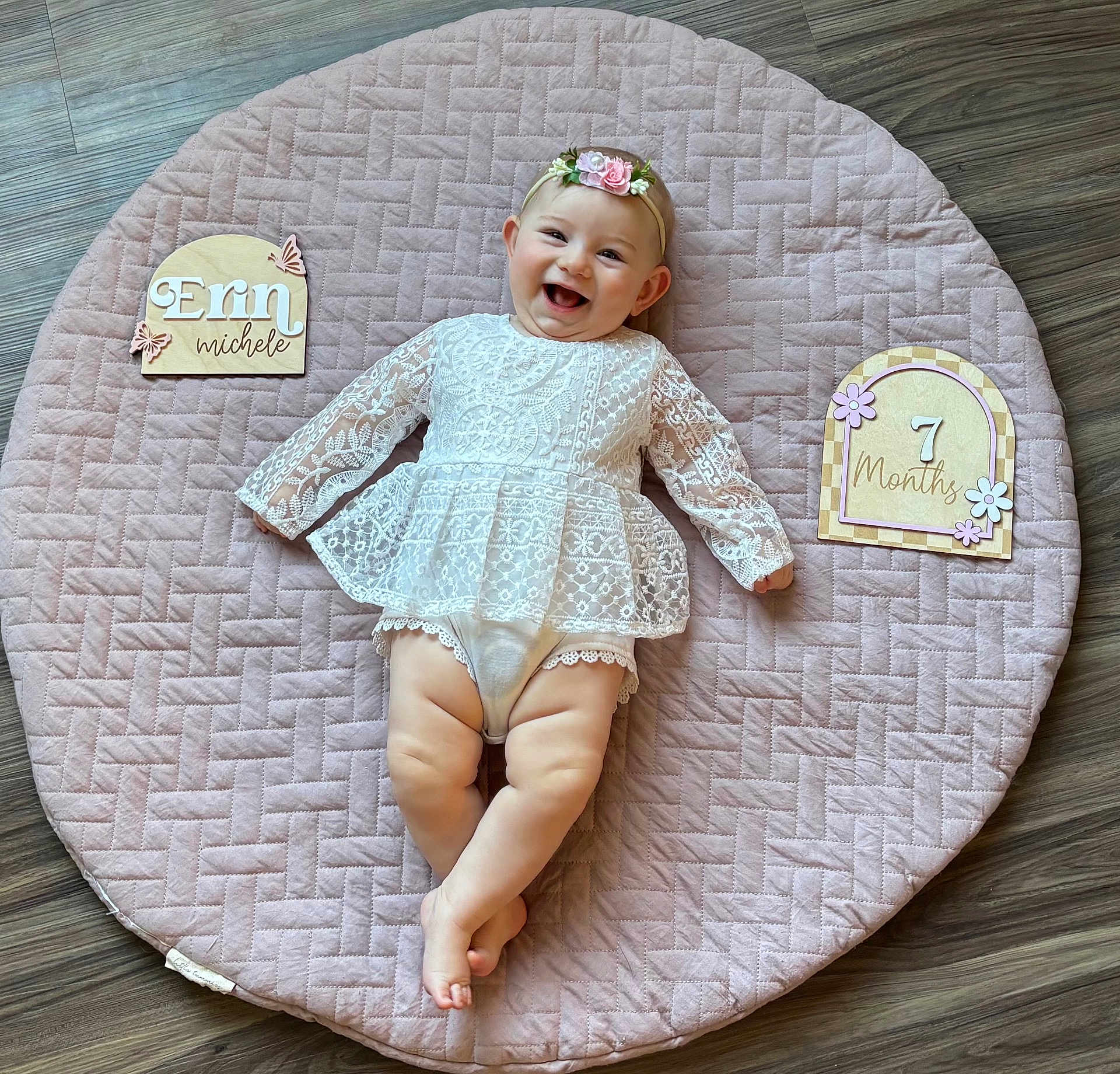 Erin joined the competition — help win amazing prizes! baby, infant, smiling, happy, girl, lace_dress, headband, flower, quilted_mat, pink, wooden_floor, milestone, age_sign, name_sign, crawling_mat, cute, portrait, child, indoor, celebration