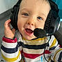 airplane_graphic, baby, blue_eyes, cheeks, child, closeup, colorful_clothing, hand, headphones, headset, indoor, infant, microphone, open_mouth, playful, portrait, seat, smile, striped_shirt, toddler