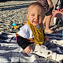Léandro a rejoint le concours — aidez-le/la à gagner de superbes lots ! baby, beach, bib, blanket, child, clothing, cup, family, hand, happy, legs, outdoor, person, sand, sitting, smile, striped_towel, sunlight, toddler, toy