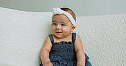 Elysia is registered to the contest to win money with this photo: baby, barefoot, child, couch, cozy, cute, denim_dress, girl, happy, headband, indoor, infant, portrait, sitting, skin, smile, sofa, soft_texture, white_headband, young_child