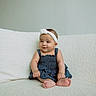 baby, infant, child, girl, denim_dress, headband, white_headband, sitting, couch, sofa, indoor, smile, happy, cute, portrait, soft_texture, cozy, barefoot, skin, young_child