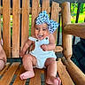 baby, child, smile, happy, sitting, wooden_swing, outdoor, bow, white_overalls, feet, wood, sunlight, nature, playful, infant, cute, portrait, fun, person, daytime