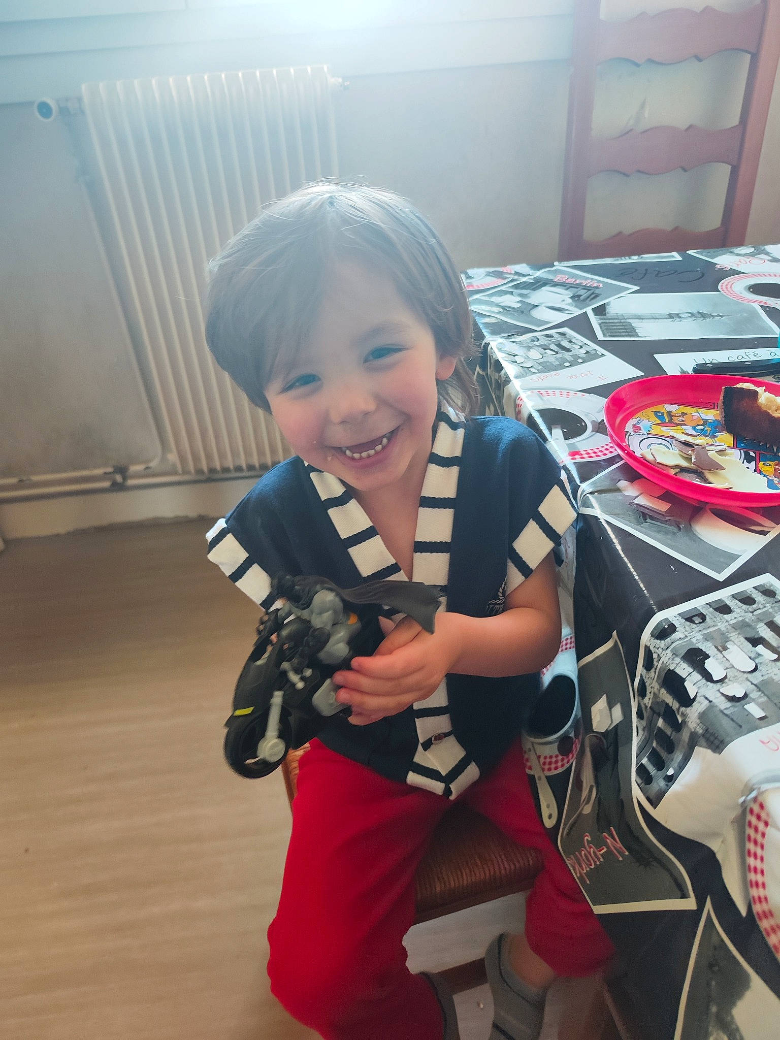 Joao a rejoint le concours — aidez-le/la à gagner de superbes lots ! audio_equipment, carmine, chair, child, fictional_character, flooring, fun, happy, joy, machine, person, personal_protective_equipment, recreation, room, sitting, smile, table, toddler