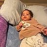 Jace is registered to the contest to win money with this photo: baby, infant, pillow, bed, blanket, clothing, sweatshirt, pants, pattern, cute, child, person, indoor, relaxing, portrait, young, sleepwear, comfort, skin, face