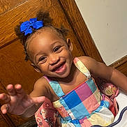 Jamaria joined the competition — help win amazing prizes! child, toddler, girl, smiling, happy, portrait, high_chair, colorful_dress, blue_bow, curly_hair, reaching, indoor, wooden_door, wall, toy, baby, sitting, face, laughter, family_photo