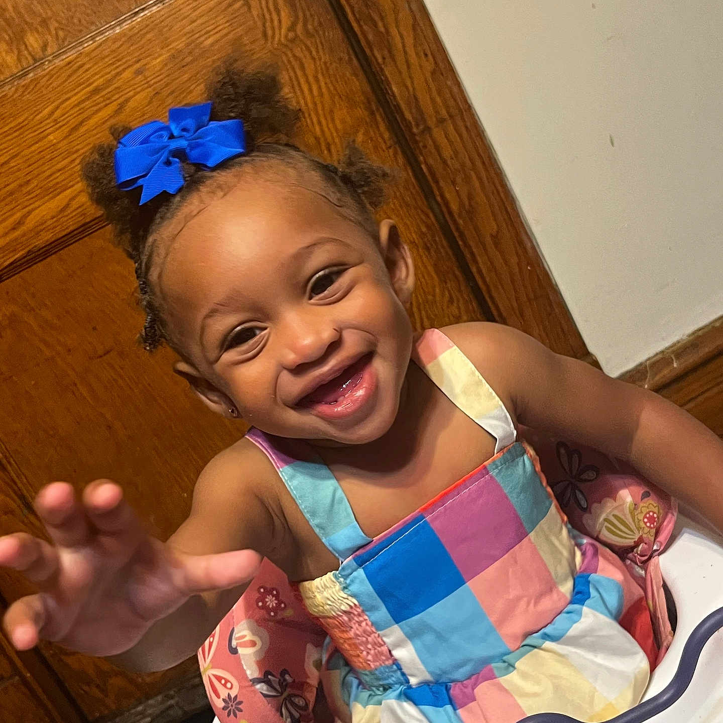 Jamaria joined the competition — help win amazing prizes! child, toddler, girl, smiling, happy, portrait, high_chair, colorful_dress, blue_bow, curly_hair, reaching, indoor, wooden_door, wall, toy, baby, sitting, face, laughter, family_photo