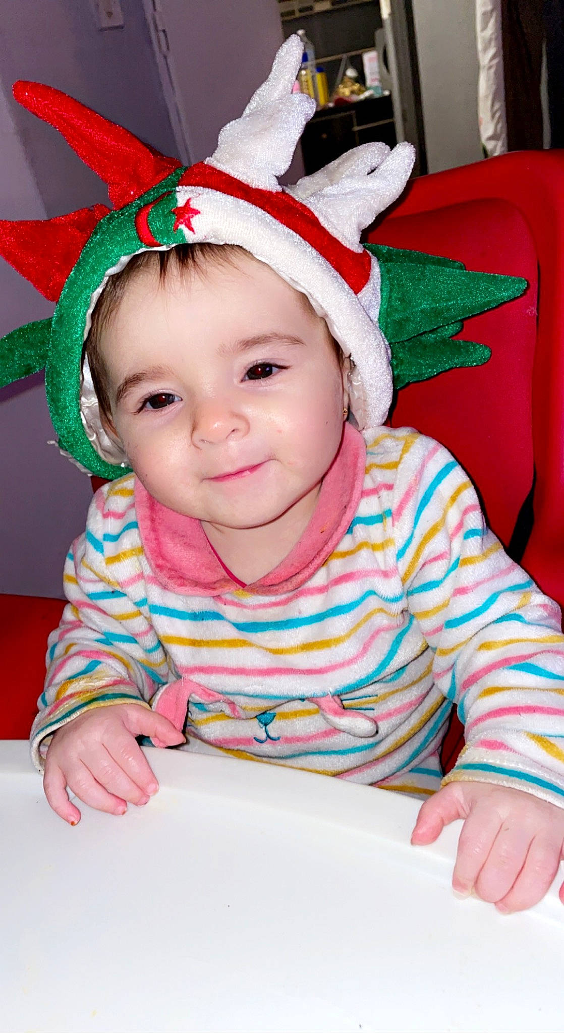 Shirine participe au concours pour gagner de l'argent avec cette photo : baby, baby_toddler_clothing, child, christmas_decoration, christmas_ornament, costume_hat, event, fun, green, happy, headwear, holiday, holiday_ornament, joy, person, pink, product, red, skin, sleeve