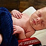 Carter is registered to the contest to win money with this photo: baby, newborn, sleeping, blanket, cloth, wagon, red_wagon, hand, skin, face, infant, rest, comfort, soft, cozy, indoors, closeup, portrait, peaceful, child
